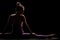 Fit girl practicing yoga in a studio. Half silhouette side lit fitness model