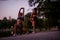 Fit girls, training together at night in a green park. They warm up, stretch arms, legs, and spines, preparing for a