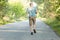 Fit grey haired mature male jogs on road, being photographed in motion, has physical exercises early in morning, wants to have hea