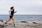 Fit and healthy young woman running along shoreline