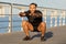 Fit man in black activewear performs squats at seaside outdoor