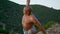 Fit man stretching arms in evening green mountain. Focused athlete training yoga