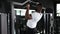 Fit and muscular african man pulling up on horizontal bar in a gym.