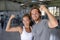 Fit power couple happy flexing strong arms showing off success training at fitness gym - Smiling Asian woman