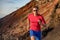 Fit runner man sport athlete trail, running outside on volcano mountain in desert. Motivation and focus during exercise. Fitness