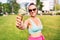 Fit slim woman showing ice cream cone in city park in summer. Happy smiling portrait of young laughing model and melting icecream.