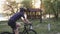 Fit sportive female cyclist on a bicycle in the city park before sunset. Cycling concept. Slow motion