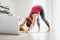 Fit sporty healthy woman on mat in Downward-Facing Dog Adho Mukha Svanasana pose, doing breathing exercises, watching online yoga