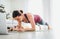 Fit sporty healthy woman on mat in low plank Chaturanga Dandasana yoga pose, doing breathing exercises, watching online yoga class