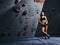 Fit sporty student girl in shorts and sports bra leaning on bouldering wall at the gym.