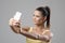 Fit sporty young woman in tank top with ponytail taking selfie photo looking at phone