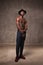 Fit strong physique African American young man wearing black hat and trousers posing dancing