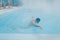 Fit swimmer male training swim in open winter swimming pool with fog. Geothermal outdoor spa concept,