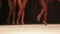 Fit tanned legs of beautiful fitness models walking on stage in high heel shoes