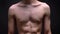 Fit topless body of caucasian sportsman standing straight iat the camera on black fond