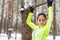 Fit woman athlete performing pull ups in a bar. Winter street outdoor training workout.