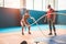 Fit woman with battle rope in functional training fitness gym - Tattooed personal trainer motivating female athlete inside