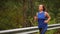 Fit woman in blue sport clothes running outdoors. Sportive woman jogging on mountain road in the morning as part of her daily rout