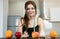 Fit woman with centimeter round neck wearing black sports top standing in the kitchen lookingat cakes and fruits on the table,