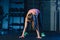 Fit woman in colourful sportswear doing burpees on a exercise mat in a grungy industrial type space