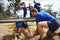 Fit woman crawling under the net during obstacle course while fit people cheering