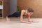 Fit woman doing yoga or pilates exercise standing in plank pose called phalankasana working out on floor in living room