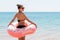 Fit woman with donut inflatable ring is walking into the sea to swim