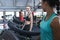 Fit woman interacting with her female friend while exercising on treadmill