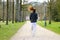 Fit woman jogging through a wooded park in spring