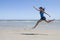 Fit woman leaping mid air on a beach