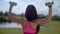 Fit woman lift weights outdoors. Back of woman exercising with dumbbells in park