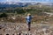 Fit woman standing on alpine trail enjoying mountain vally view.