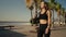 Fit woman with yoga mat and going to training. Caucasian woman walking on beach at the morning.