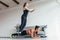Fit women training home. Girl jumping over her friend while woman performing plank position.
