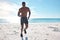 Fit young black man running and jogging on sand at the beach in the morning for exercise. One strong male bodybuilder
