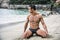 Fit young bodybuilder in bathing suit on the beach