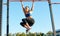 Fit young female doing pull ups exercises on crossbar outdoors. Athlete woman training hard on the bar at sportground. People,