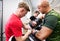 Fit young man in gym with his trainer preparing for boxing.