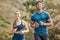 Fit young man and woman running together outdoors. Interracial couple and motivated athletes doing cardio workout while