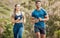 Fit young man and woman running together outdoors. Interracial couple and motivated athletes doing cardio workout while