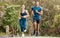 Fit young man and woman running together outdoors. Interracial couple and motivated athletes doing cardio workout while