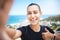 A fit young mixed race female jogger showing a thumbs up gesture outside while taking a selfie after a good exercise