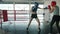 Fit young sportswomen doing sports sparring inside boxing ring wearing helmets and gloves