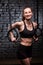 Fit young sporty woman holding gymnast rings and smiling at the cross fit gym against brick wall.