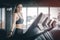 Fit young woman caucasian running on machine treadmill workout in gym. Glad smiling girl is enjoy with her training process.