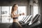 Fit young woman caucasian running on machine treadmill workout in gym. Glad smiling girl is enjoy with her training process.