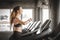 Fit young woman caucasian running on machine treadmill workout in gym. Glad smiling girl is enjoy with her training process