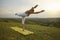 Fit young woman doing yoga on mountain top in morning. Beautiful girl in sportswear standing in warrior pose outdoors