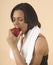 Fit young woman eating an apple with a towel around her shoulder
