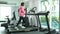 Fitness Asian woman in pink overcoat speedy running on track treadmill machine